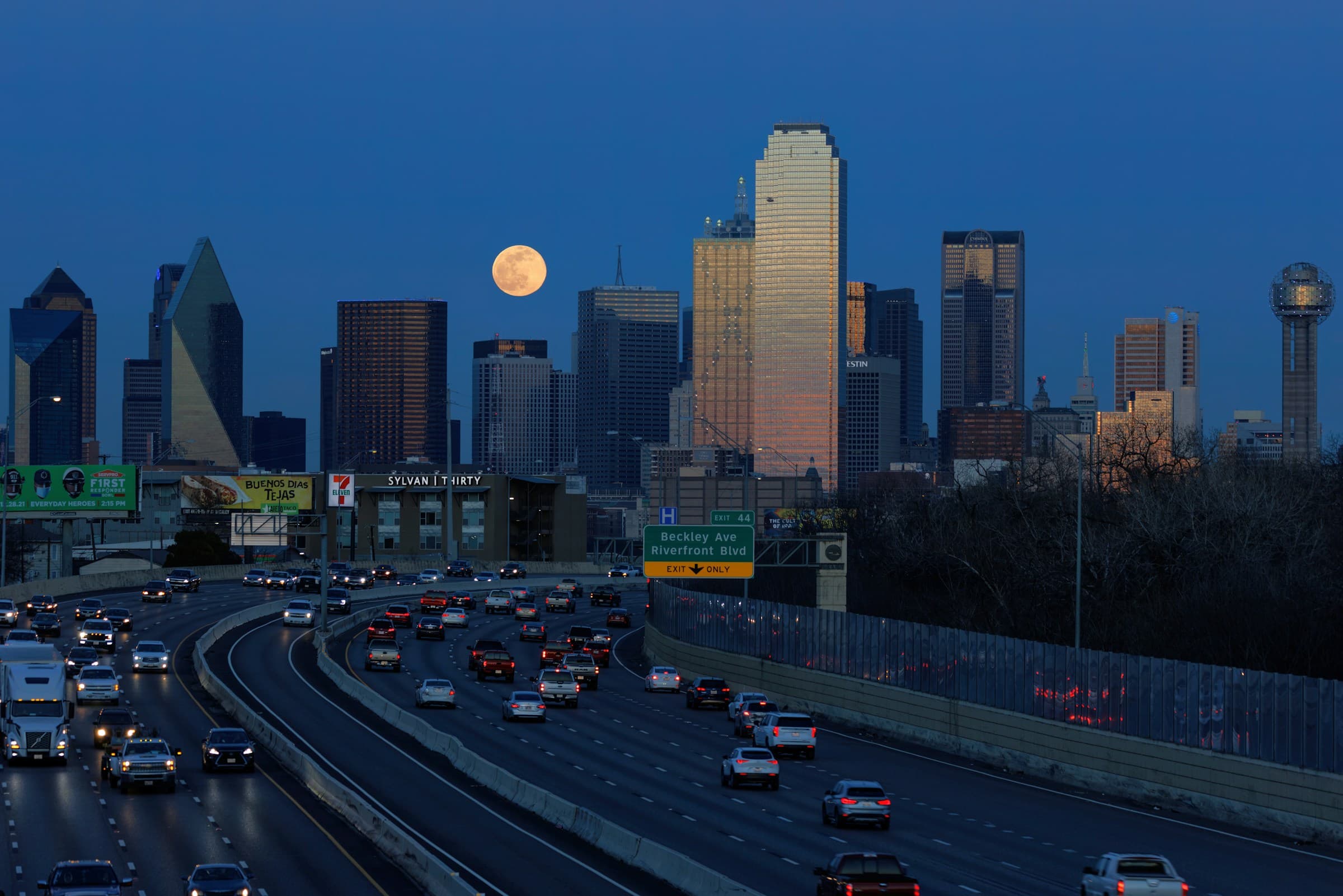 Full moon rising over the Dallas skyline above I-30