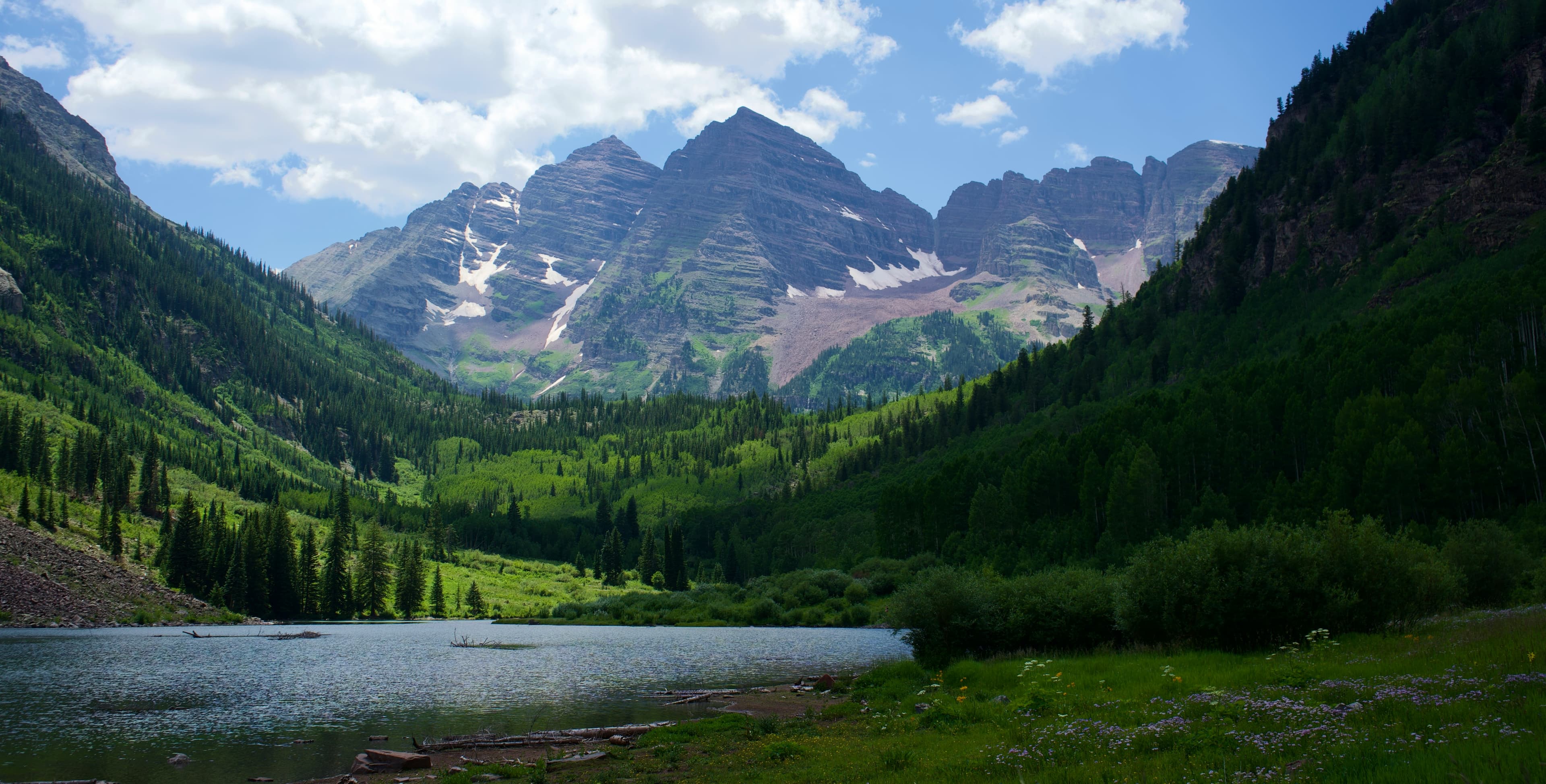 Maroon Bells, Colorado — snow-capped peaks above a green summer valley